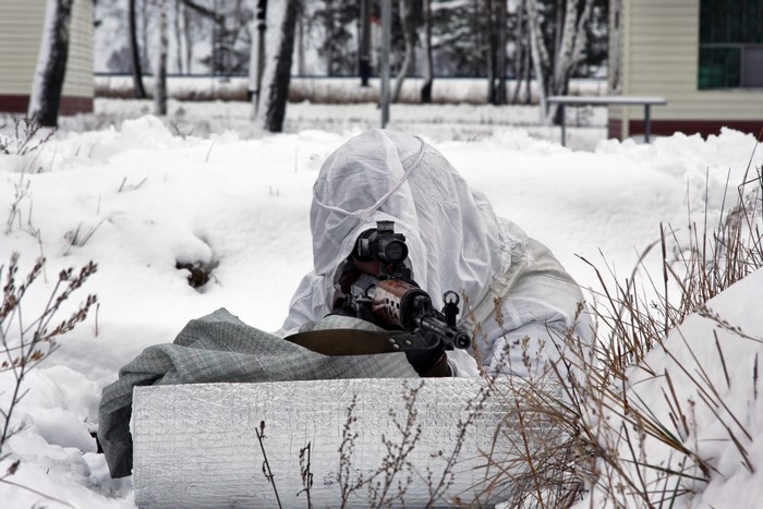 Soldier in camouflage aiming a rifle in the snow