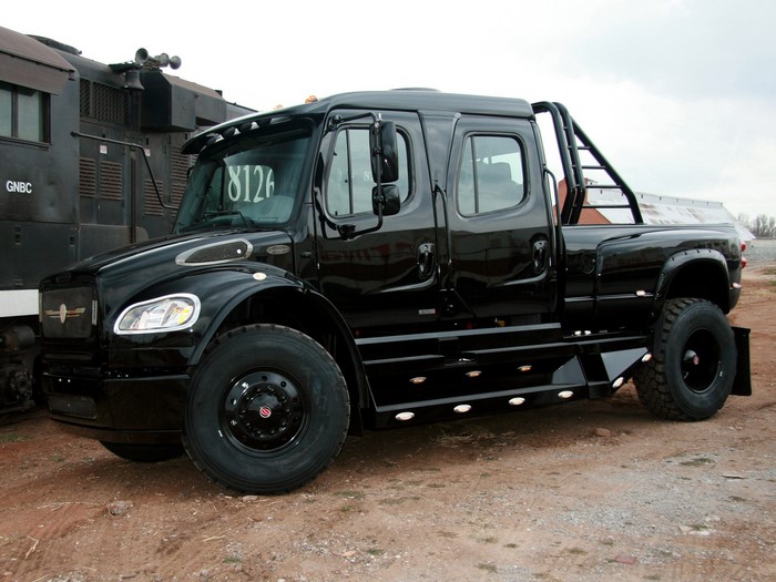 Black custom crew cab truck parked next to a train