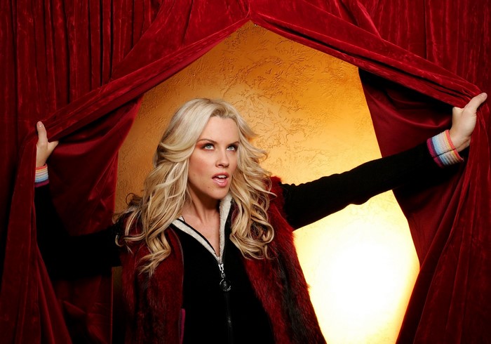 Jenny McCarthy posing behind red curtains