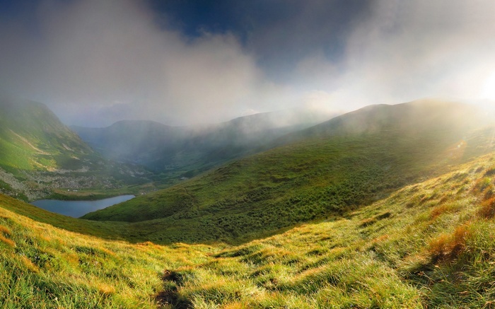 Misty mountain valley with a lake and sunbeams