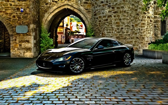 Black Maserati GranTurismo parked under stone archway