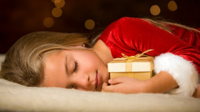 Girl in Santa costume sleeping with gift