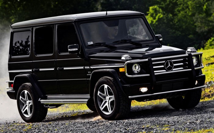 Black Mercedes-Benz G-Wagon driving on a dirt road