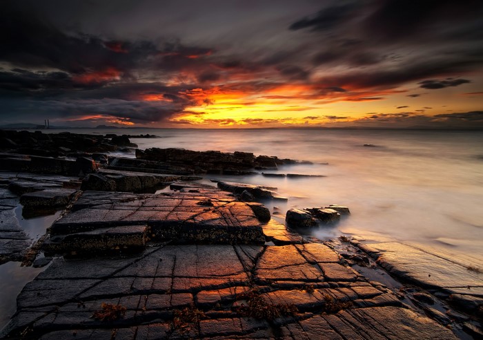 Sunset over rocky shore with dramatic clouds