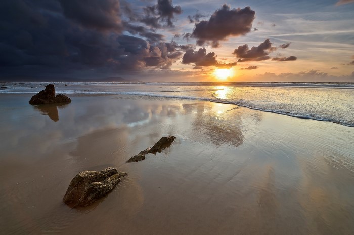 Sunset over a rocky beach with reflections