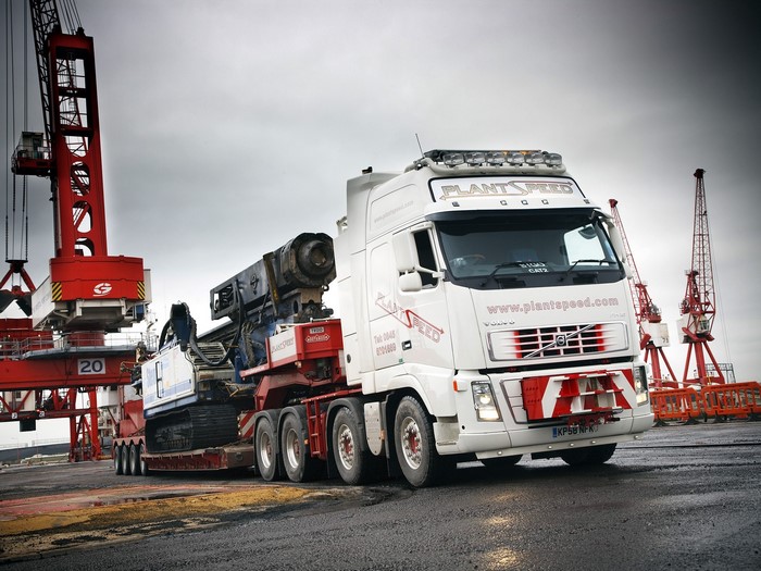 Volvo truck carrying heavy machinery at a port