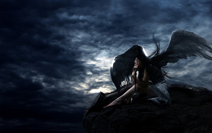 Dark angel sitting on a rock