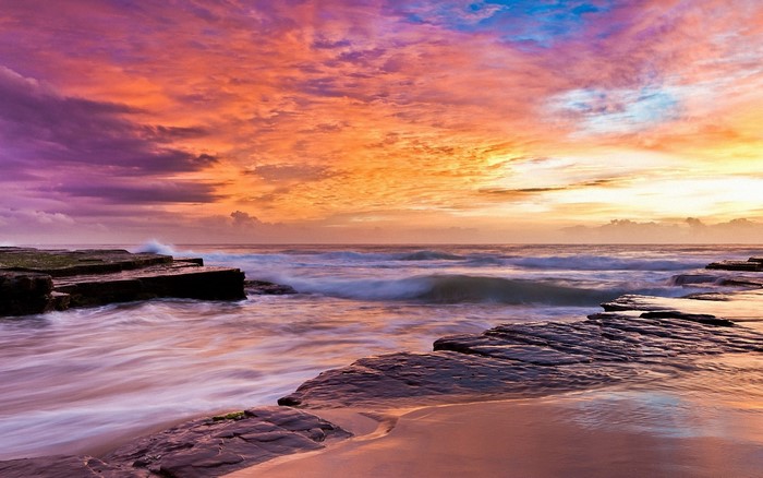Ocean waves crashing on rocks at sunset