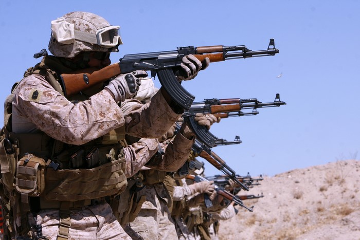 Soldiers aiming AK-47 rifles in a desert
