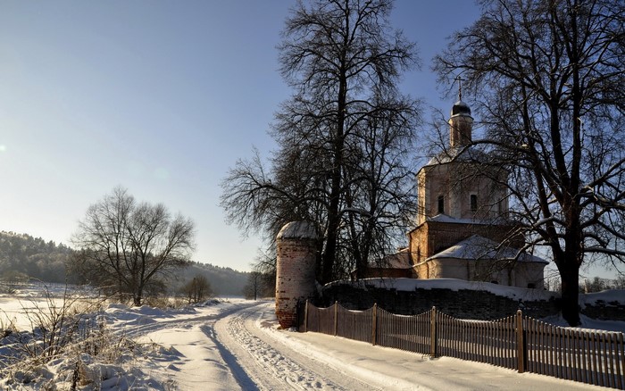 Winter road leading to a church with a stone fence