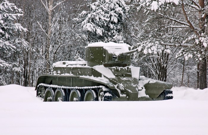 A green tank covered in snow in a winter forest