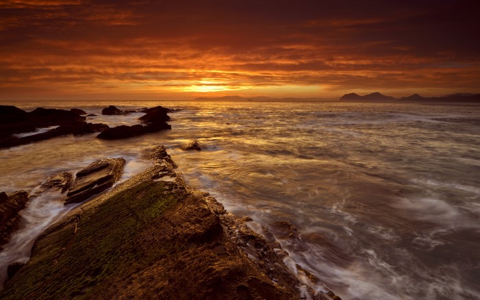 Sunset over rocky coastline with ocean waves