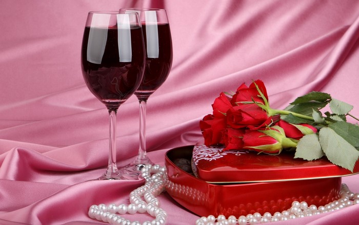 Two glasses of red wine with roses and a heart-shaped box