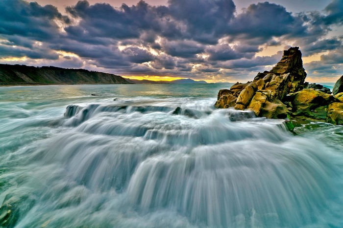 Ocean waves crashing on rocks at sunset
