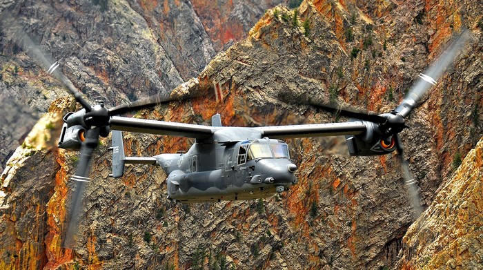 US military Osprey aircraft flying through a canyon