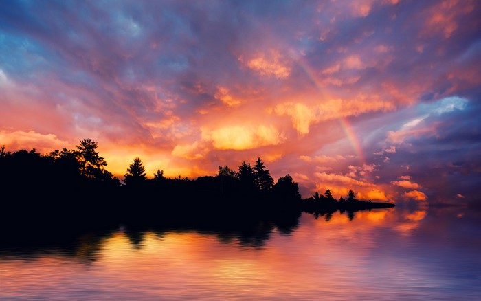Sunset over a lake with a rainbow