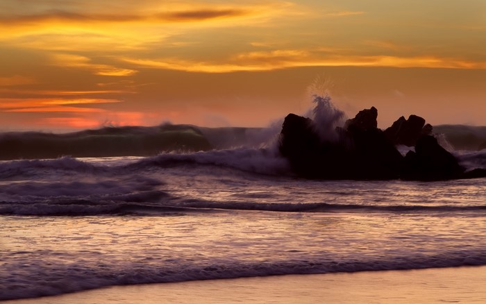 Waves crashing on rocks at sunset