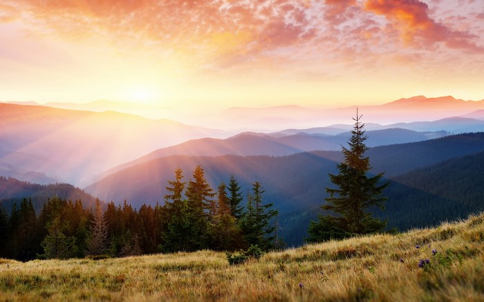 Mountain range at sunrise with sunbeams