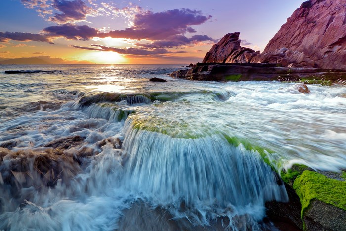 Ocean sunset with rocky shore and waterfall