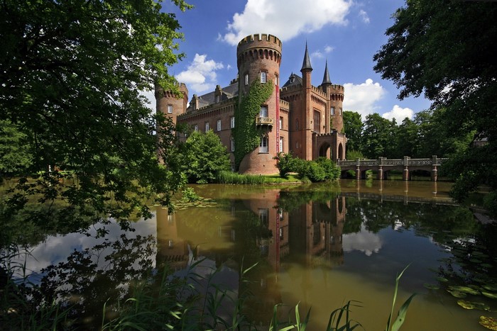 Castle Moyland reflected in water with trees and bridge