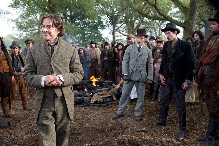 Sherlock Holmes and a crowd gathered around a bonfire