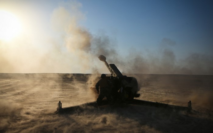 Soldier fires a cannon in a dusty landscape