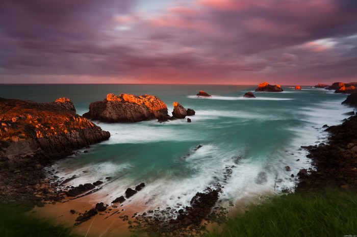 Rocky coastline with ocean waves at sunset