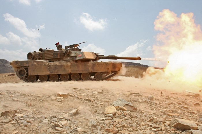 Tank firing a projectile in a desert landscape