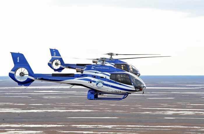 Two blue Hudson Bay Helicopters flying over landscape