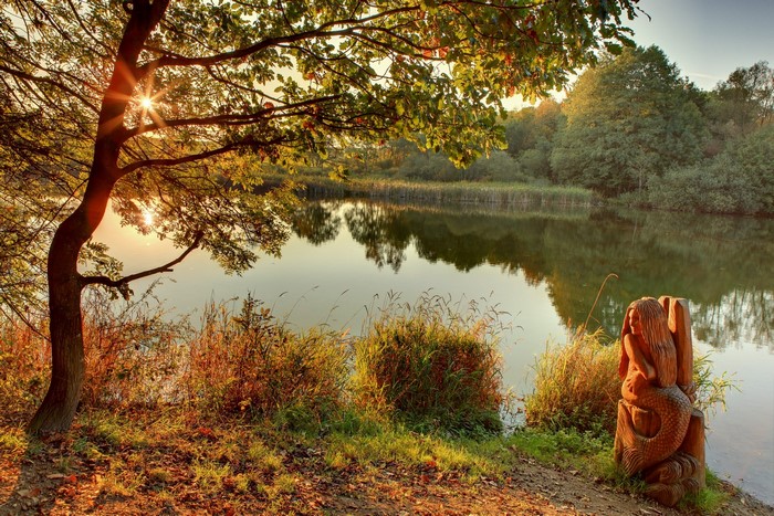 Wooden Mermaid Sculpture by a Lake at Sunset