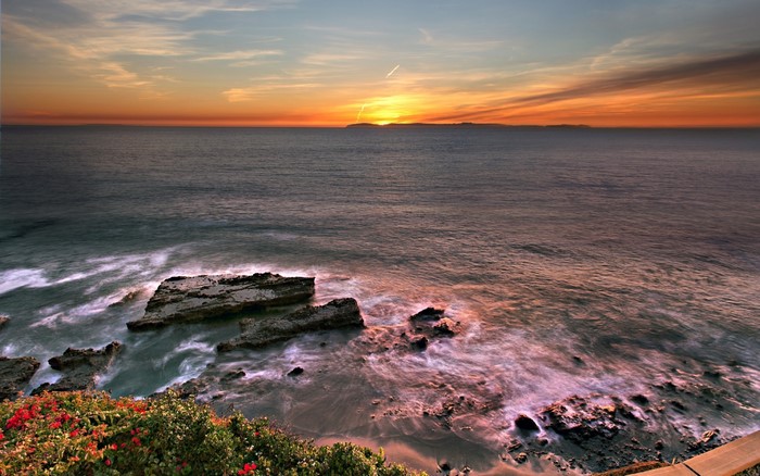 Sunset over the ocean with islands on the horizon