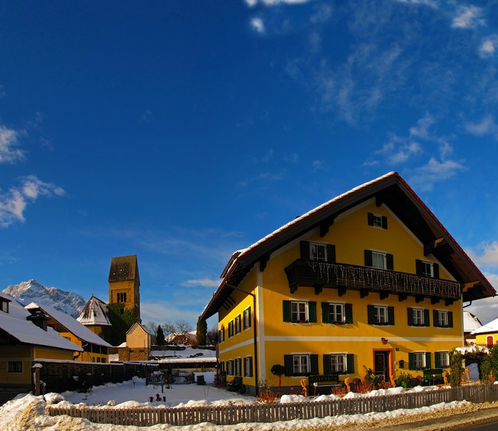 Yellow house and church tower in Austria with snow