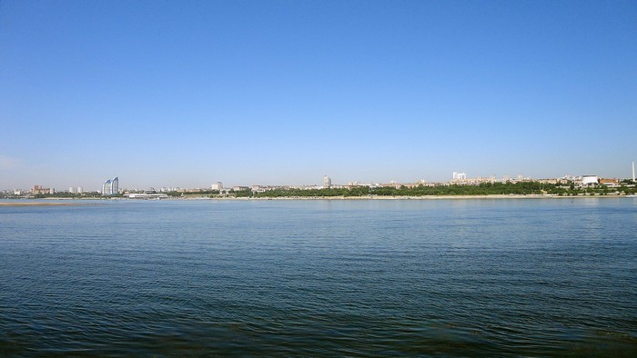 Volgograd cityscape across a wide river under a clear blue sky