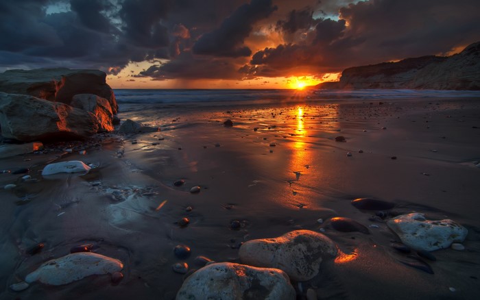 Sunset over a rocky beach with dramatic clouds
