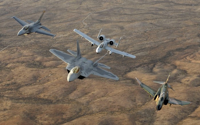 Four military jets flying over desert terrain