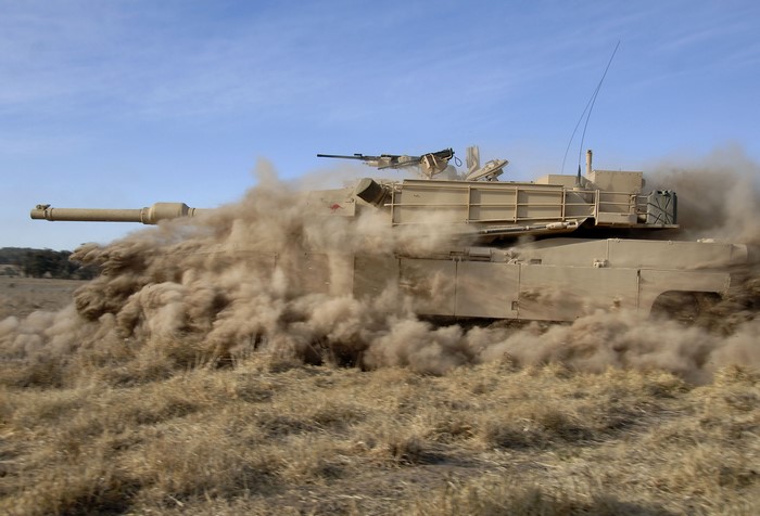 M1 Abrams tank driving through dust