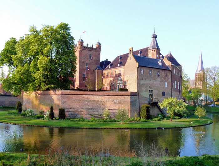 Castle surrounded by a moat with a church in the background