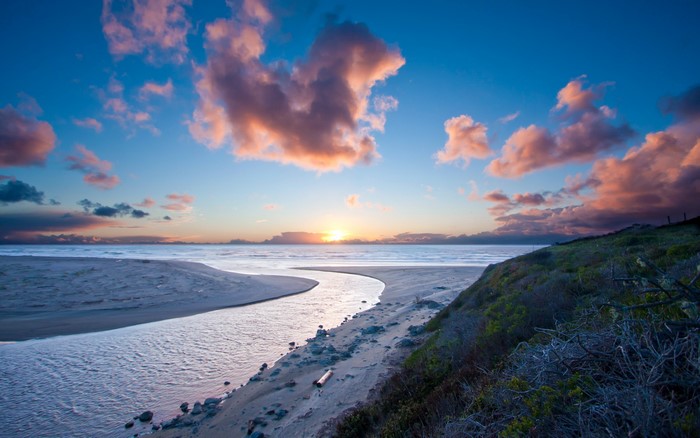 Sunset over ocean with river and clouds