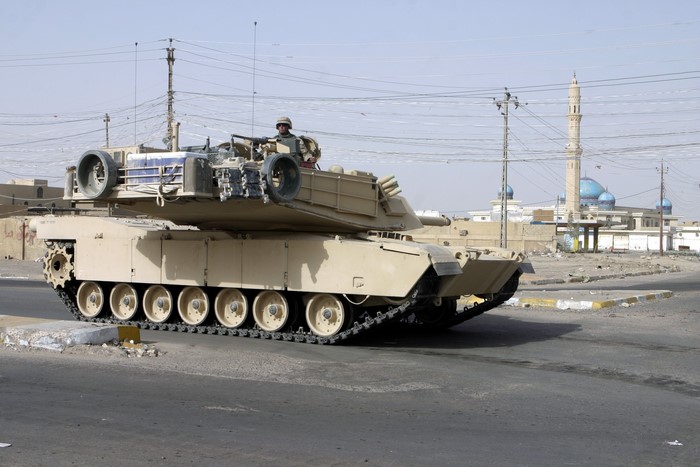 M1 Abrams tank with soldier in desert city
