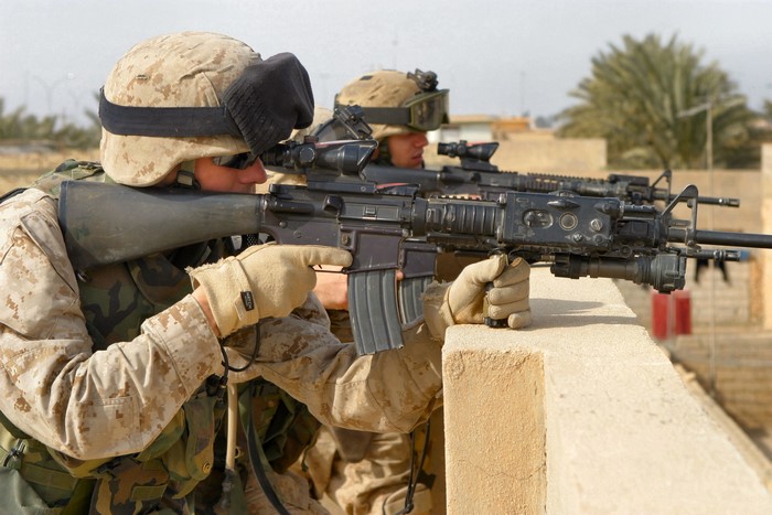 Soldiers aiming rifles over a wall