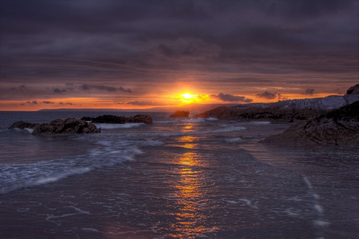 Sunset over rocky beach with ocean waves