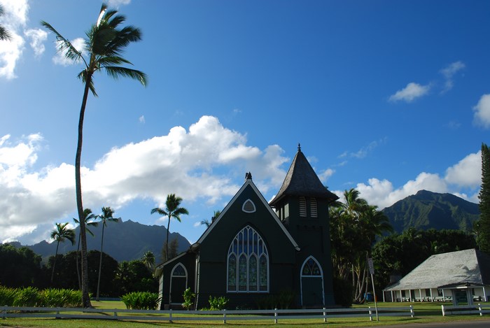 Green church with palm trees and mountains in Hawaii
