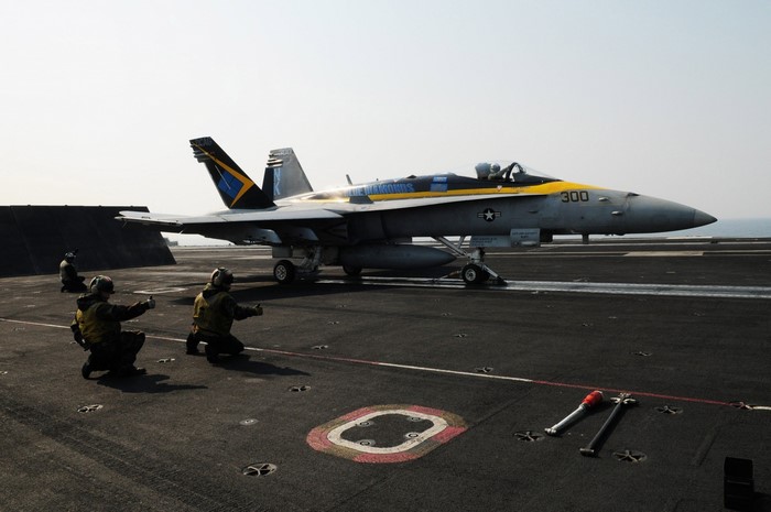 Fighter jet on aircraft carrier with crew