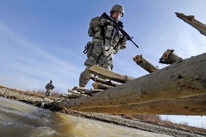 Soldiers crossing a river on a log bridge