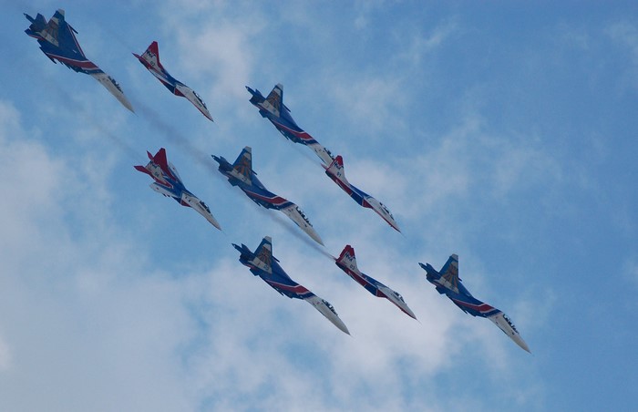 Nine fighter jets flying in formation against a cloudy sky