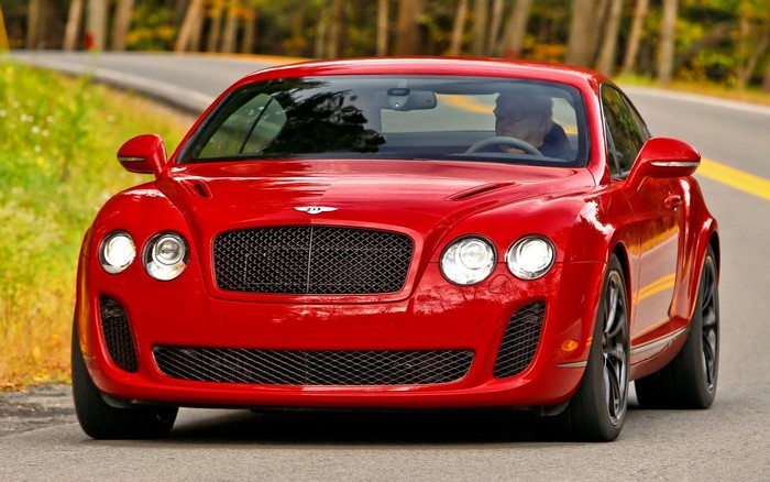 Red Bentley Continental GT driving on a road