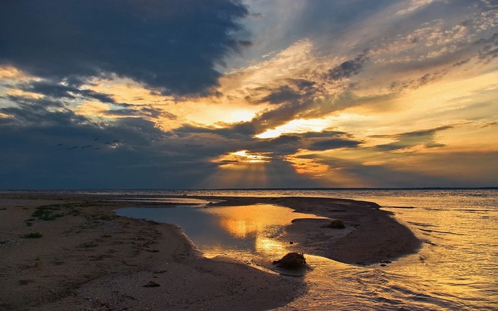 Sunset over a sandy beach with calm water