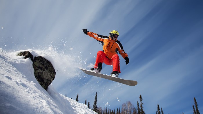 Snowboarder jumping off a snowy rock