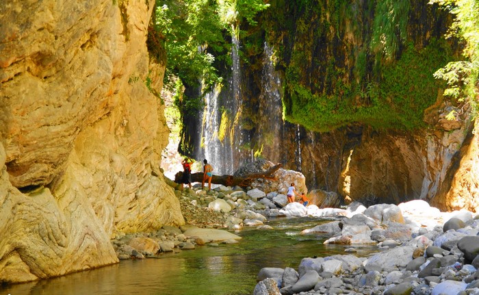 People at a waterfall in a rocky canyon