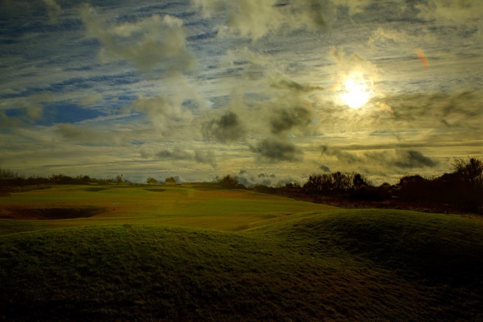 Golf course with dramatic cloudy sky at sunset